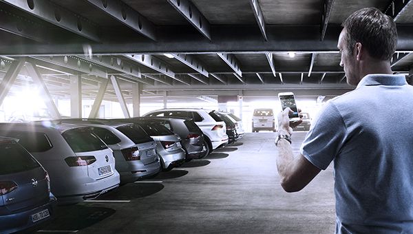 Mann mit Smartphone in einer Tiefgarage mit Autos